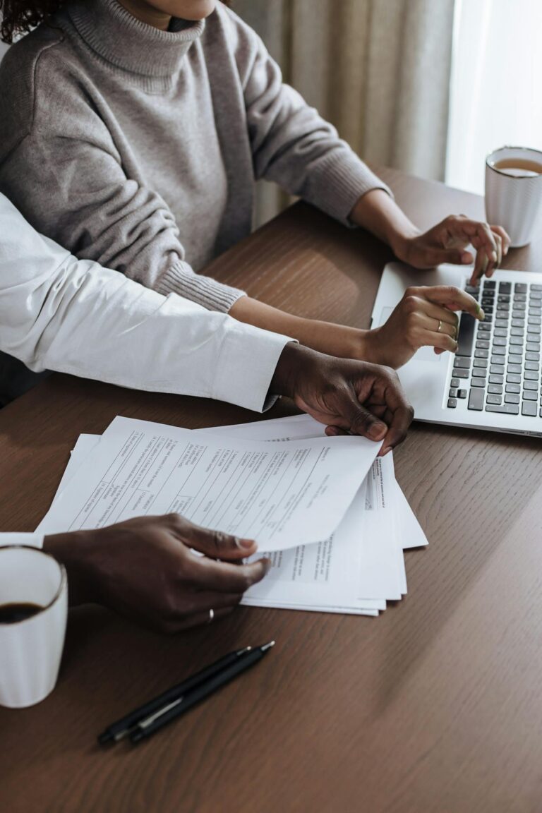 Close-up of diverse colleagues working together on a laptop in a modern office environment.